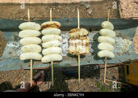 Tradizionali pacchi di foglie di banana alla griglia su una stufa a carbone nel sud-est asiatico Foto Stock