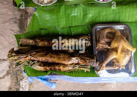 Tradizionali pacchi di foglie di banana alla griglia su una stufa a carbone nel sud-est asiatico Foto Stock