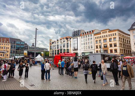 Lipsia, Germania – 7 giugno 2025: La folla si riunisce nella vivace piazza del mercato di fronte alle bancarelle di cibo e su un grande palco durante un evento pubblico nel ci Foto Stock