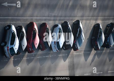 molte auto parcheggiate in fila nella riserva centrale di una strada a più corsie Foto Stock
