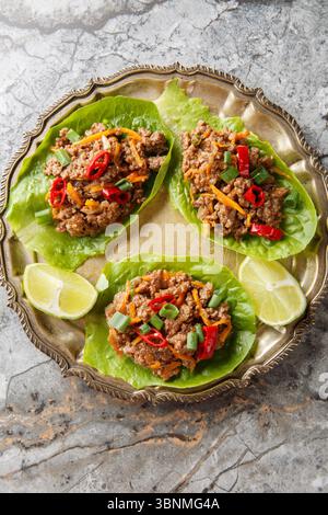 Succose tazze di lattuga di manzo tailandese da vicino sul piatto sul tavolo. Vista dall'alto verticale Foto Stock