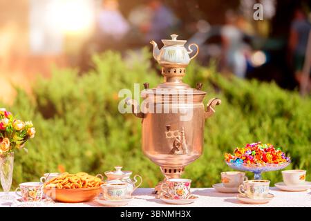 Samovar tradizionale russo con tazze e dolci sul tavolo. Foto Stock