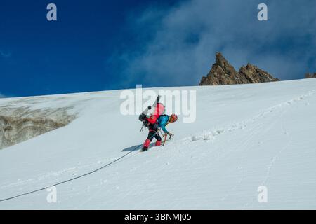 Alpinismo team di corda sul ghiacciaio neve fredda d'alta quota catena montuosa Tian-Shan arrampicata tra crepacci ramponi ascia di ghiaccio stretto crinale di neve Foto Stock