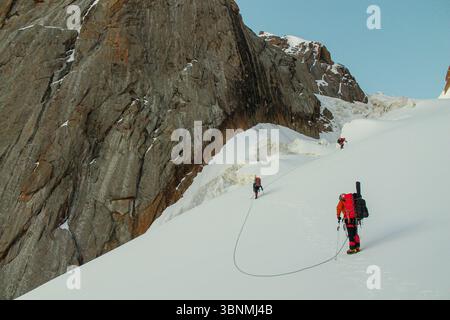Alpinismo team di corda sul ghiacciaio neve fredda d'alta quota catena montuosa Tian-Shan arrampicata tra crepacci ramponi ascia di ghiaccio stretto crinale di neve Foto Stock
