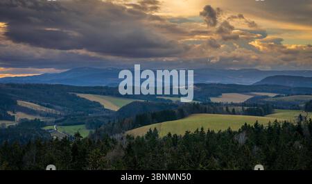 La luce del sole dell'ora d'oro bagna il paesaggio con una luce calda, evidenziando la consistenza dei campi e delle foreste Foto Stock