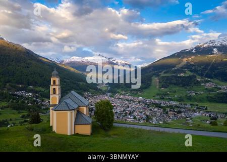 Vista di un tramonto primaverile sulla città di Bormio dalla chiesa della Madonna di Oga. Bormio, distretto di Sondrio, Valtellina, Lombardia, Italia, Europa. Foto Stock