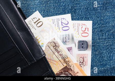 Banconote britanniche nel portafoglio. Dieci banconote da venti e cinquanta libbre parzialmente visibili. Valuta del Regno Unito su sfondo denim. Concetto finanziario. Soldi personali. Foto Stock