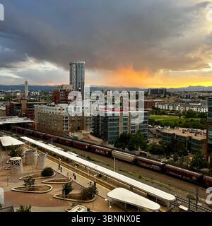 Una vista panoramica cattura un vivace skyline della città caratterizzato da vari stili architettonici, dominato da un alto grattacielo. Di seguito, una stazione ferroviaria estesa Foto Stock