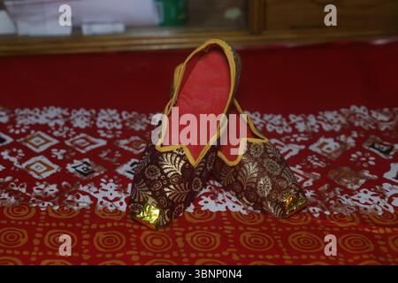 Decora le tradizionali calzature jutti indiane con decorazioni in oro Foto Stock