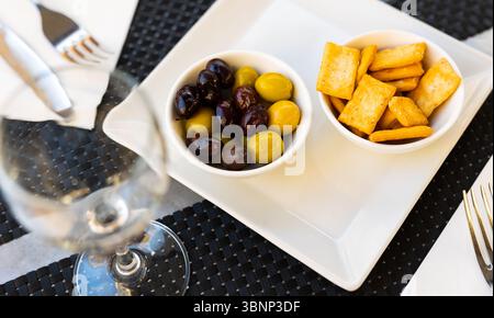 Olive nere e verdi. Patatine croccanti o cracker per uno spuntino Foto Stock