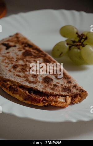 Primo piano di Quesadilla con uva su piatto Foto Stock