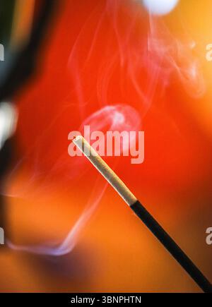 Bastoncino di incenso che brucia con un bel fumo intorno Foto Stock