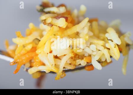 Piatto di riso colorato servito su un cucchiaio all'ora del pasto Foto Stock