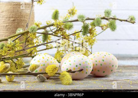 Composizione di pasqua di fioritura e rametti di salice, sanguinello e uova di Pasqua con un pattern di giallo e verde punti su una tavola di legno retrò spazio sfondo vicino Foto Stock