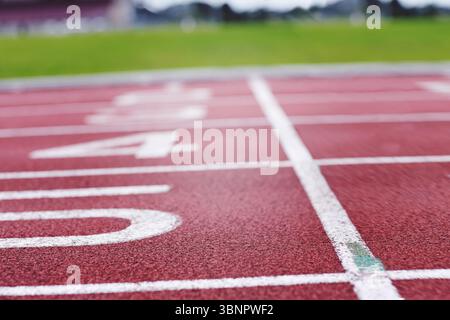 Design piatto con pista rossa con linee bianche e corsia numero 4 su sfondo verde Foto Stock