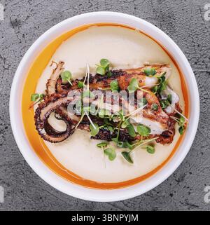Natura morta alimentare, polpo alla griglia con zuppa di crema di patate Foto Stock