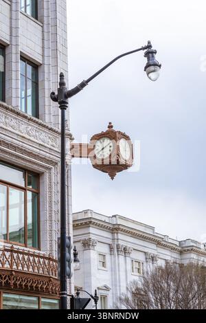 Orologio in bronzo vintage su un angolo decorato dell'edificio in un paesaggio urbano coperto Foto Stock
