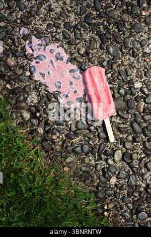 Il popsicle rosa si scioglie sul marciapiede nelle calde giornate estive Foto Stock