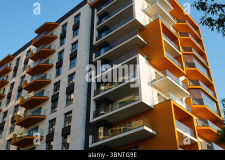 Nuovo edificio di appartamenti esterno con balconi e finestre. Design moderno in colori bianco e giallo. Foto Stock