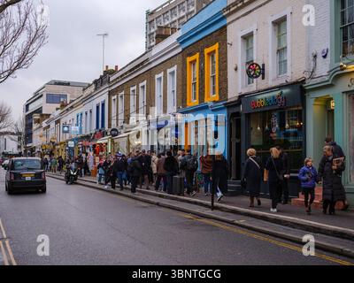 Londra, Regno Unito, 16 dicembre 2024. La folla passeggia lungo la vibrante Portobello Road, costeggiata da facciate colorate, boutique e caffetterie in un pomeriggio invernale nuvoloso Foto Stock