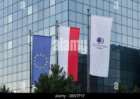 Lodz, Polonia - 2 luglio 2025: Bandiere dell'UE, della Polonia e DoubleTree by Hilton di fronte all'edificio dell'hotel a Lodz, Polonia. Foto Stock