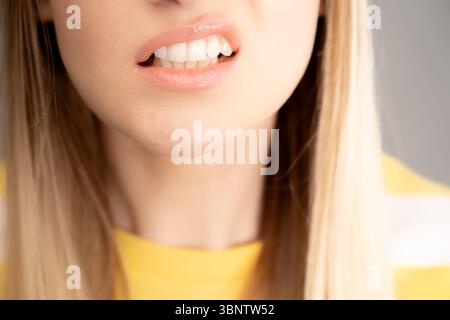 Una donna sta barando i denti e torcendo la bocca. Lo scatto è un primo piano della parte inferiore del suo viso. Foto Stock