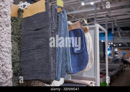 Una grande collezione di bellissimi tappeti è appesa su un rack in un negozio Foto Stock