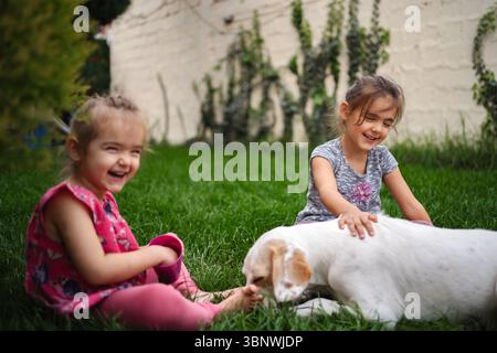 Momenti di gioia condivisi da due bambini con il loro cane giocoso Foto Stock