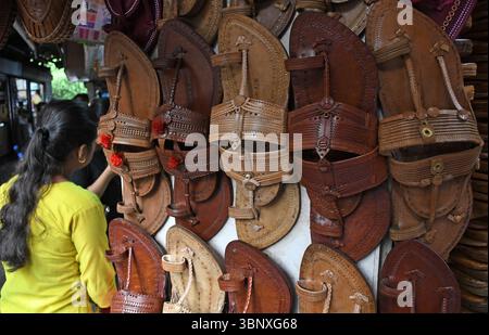Coppie di palle Kolhapuri (sandali indiani artigianali) sono tenute in vendita in un negozio a lato della strada. Il marchio italiano di moda di lusso Prada, che ha lanciato i suoi 'sandali con anello di dito', è accusato di copiare il design ispirato alle zampe Kolhapuri (sandali indiani artigianali) senza dare il dovuto credito agli artigiani indigeni che li hanno creati nel distretto di Kolhapur nel Maharashtra secoli fa. Un contenzioso di interesse pubblico (PIL) è stato depositato presso l'alta Corte di Bombay in cerca di un risarcimento per gli artigiani di Kolhapuri chappall (sandali indiani artigianali) di Prada. Foto Stock