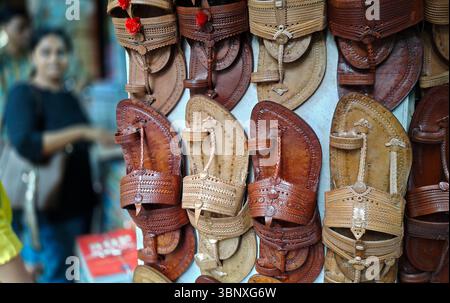 Coppie di palle Kolhapuri (sandali indiani artigianali) sono tenute in vendita in un negozio a lato della strada. Il marchio italiano di moda di lusso Prada, che ha lanciato i suoi 'sandali con anello di dito', è accusato di copiare il design ispirato alle zampe Kolhapuri (sandali indiani artigianali) senza dare il dovuto credito agli artigiani indigeni che li hanno creati nel distretto di Kolhapur nel Maharashtra secoli fa. Un contenzioso di interesse pubblico (PIL) è stato depositato presso l'alta Corte di Bombay in cerca di un risarcimento per gli artigiani di Kolhapuri chappall (sandali indiani artigianali) di Prada. Foto Stock