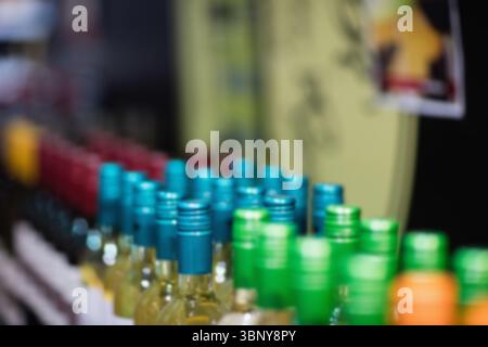 I flaconi in vetro vengono esposti in uno scaffale piatto per la vendita al dettaglio, con tappi a vite colorati Foto Stock
