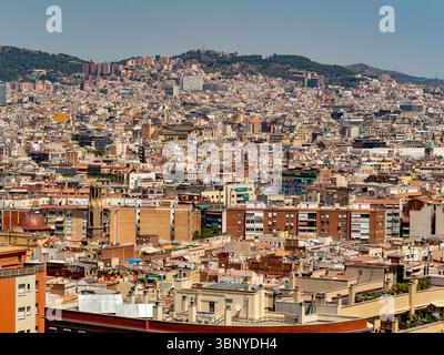 Una vista sopraelevata sulla vasta e fitta collezione di tetti residenziali di Barcellona, Spagna, che mostra il paesaggio urbano unico della città. Foto Stock