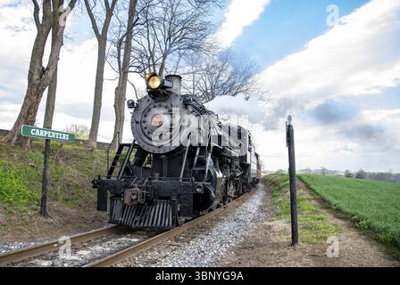 Ronks, Pennsylvania, 15 aprile 2025 - Una storica locomotiva a vapore si snoda lungo la ferrovia vicino a Carpenters, circondata da vegetazione lussureggiante e alberi, con Foto Stock