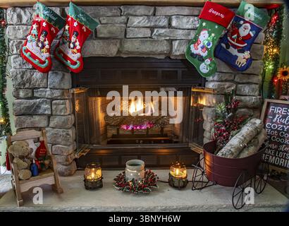 Un caminetto con una calza rossa e verde appesa ad esso. La calza è decorata con un babbo natale e un pupazzo di neve Foto Stock