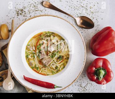 Natura morta alimentare, zuppa di pollo con spaghetti e verdure in un recipiente bianco Foto Stock