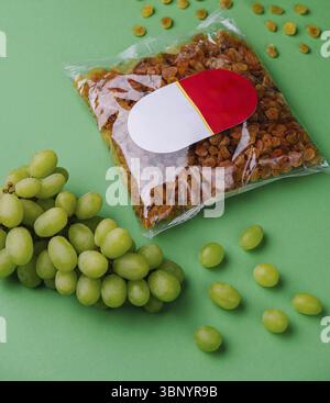 Uva passa confezionata e uva su sfondo verde Foto Stock