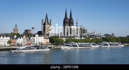Colonia, Germania giugno 25 2024: Molte grandi barche da escursione sulle rive del reno, con il pittoresco scenario della città vecchia di colonia Foto Stock