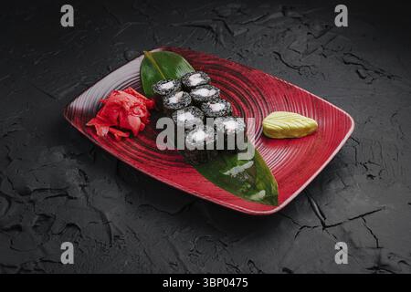 Natura morta del cibo, sushi involtini realizzati con delicatezza sono disposti in modo ordinato su un piatto rosso. Accompagnato da wasabi e zenzero sottaceto, la presentazione Foto Stock