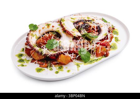 Natura morta alimentare, i tentacoli di polpo grigliati si trovano in cima a un letto di verdure arrostite, guarniti con erbe e formaggio su un piatto bianco, evidenziando un colo Foto Stock