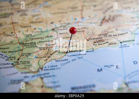 Primo piano di una spilla rossa che segna la città di Málaga su una mappa mondiale dell'atlante della Spagna, che rappresenta la pianificazione del viaggio, la destinazione e l'esplorazione Foto Stock