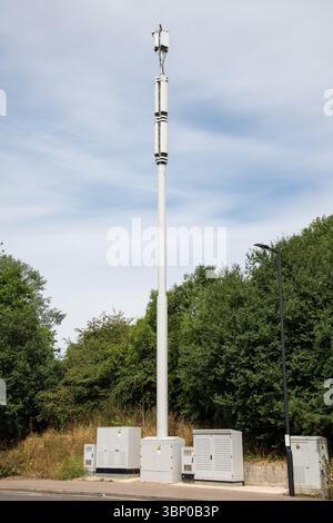 Montante monopolare per telefoni cellulari che si innalza sopra i tetti di Smeaton Road a Enfield Lock, Londra. Infrastrutture di telecomunicazione urbane su una strada residenziale Foto Stock