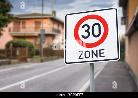 Zona segnale limite di velocità 30. Segnale di sicurezza stradale tedesco vicino agli edifici residenziali. Simbolo del codice del traffico sul palo. Tranquillo avvertimento di vicinato in Europa. Foto Stock