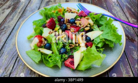 Frutta fresca e insalata di noci - verdure miste con bacche, mele e Crunch su tavola in legno rustico Foto Stock