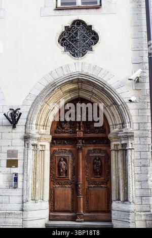 Porta ornata in legno intagliato con arco in pietra e finestra gotica Foto Stock