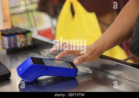 Pin maschio a pressione manuale sulla macchina EDC sul cassiere, primo piano della mano che inserisce il codice pin nel terminale del lettore di schede Foto Stock