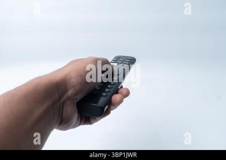 Primo piano di una mano asiatica con telecomando isolato su sfondo bianco. Foto Stock