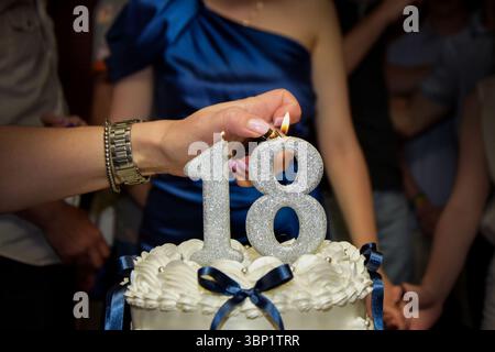 Accendere le candele di compleanno numero 18 su una torta Foto Stock