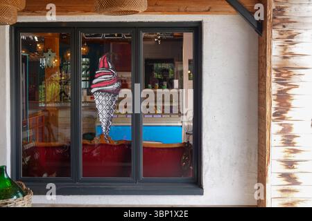 Colorata entrata della gelateria con grande decorazione a cono e vetrina Foto Stock