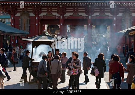 I credenti si affollano intorno a un bruciatore di incenso per ungere se stessi con fumo sacro sperando di guarire i disturbi corporei al Tempio Sensoji ad Asakusa, Tokyo. Foto Stock