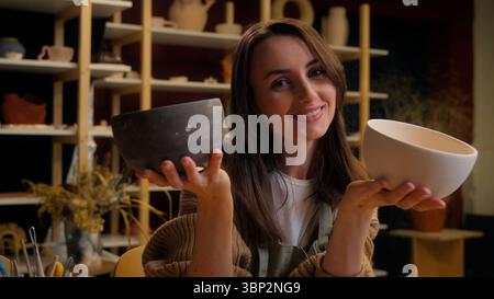 Una donna tiene abilmente due ciotole artigianali in uno studio di ceramica Foto Stock